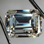 An emerald cut diamond requiring a damage report. Under the microscope one can see not only the internal crystal inclusions but a blow to the table.